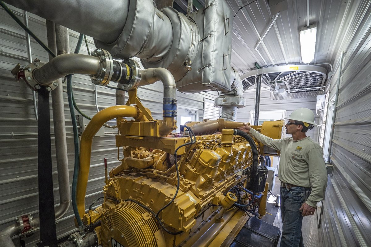 An engineer checking a power-generation engine inside a generator building